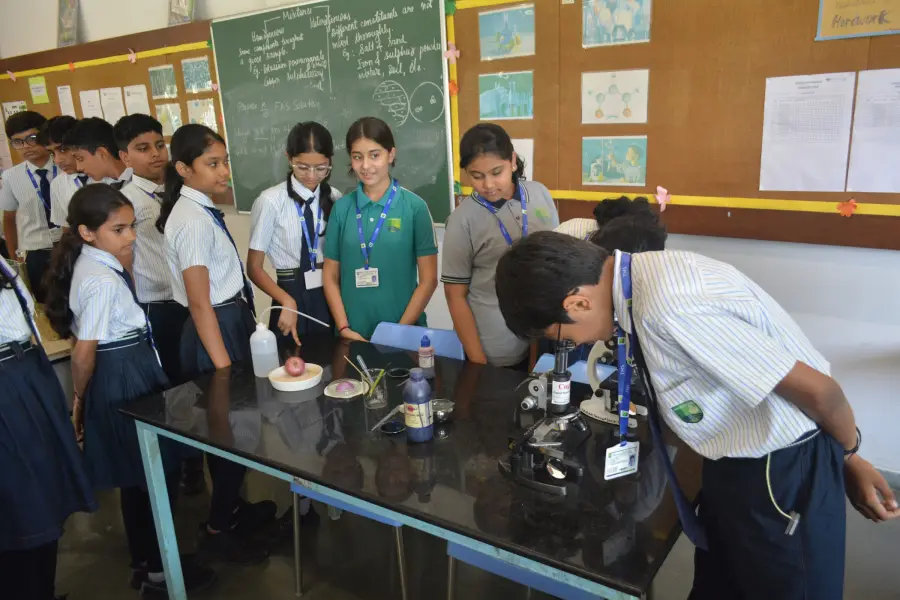 Middle-school students gathered around microscopes